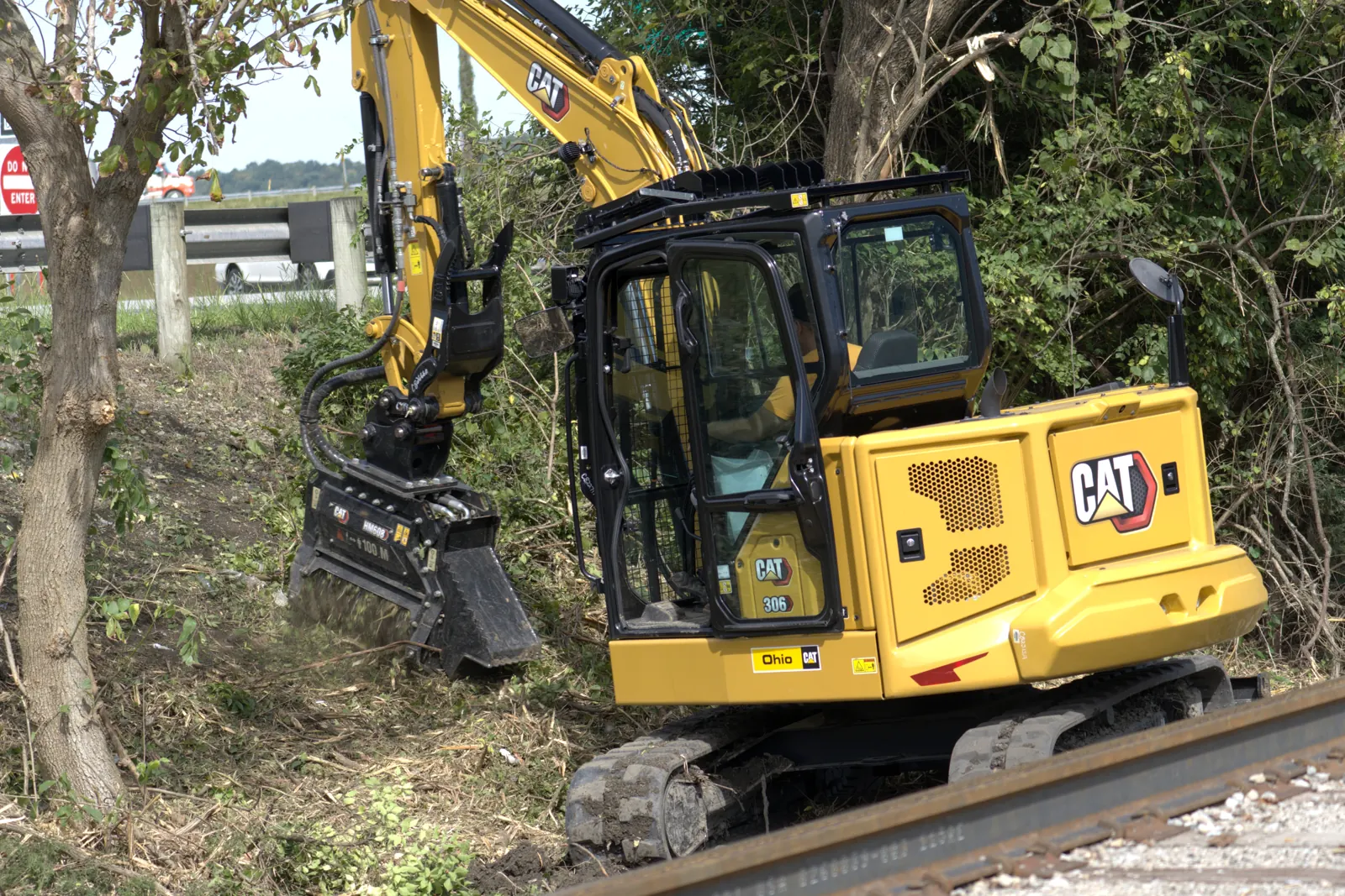 CAT 306 excavator mulcher clearing brush and saplings along a right-of-way corridor