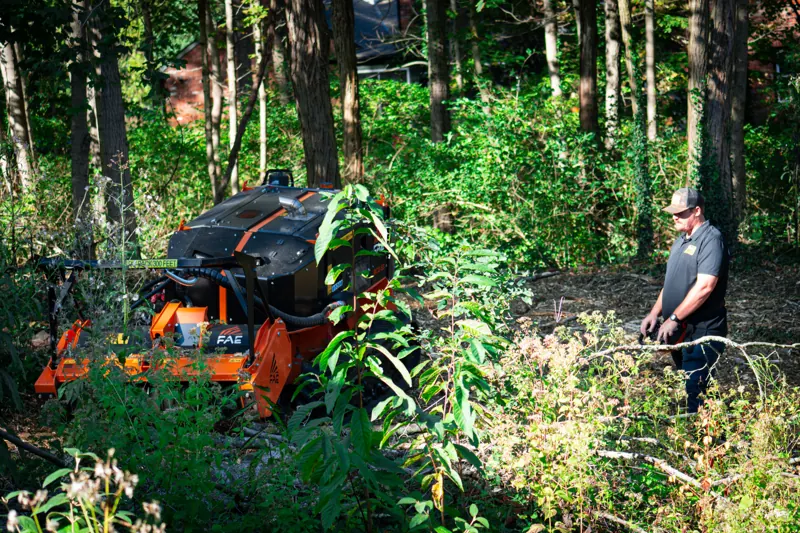 FAE RCU 55 remote-controlled mulcher in tall brush with the operator and remote behind it