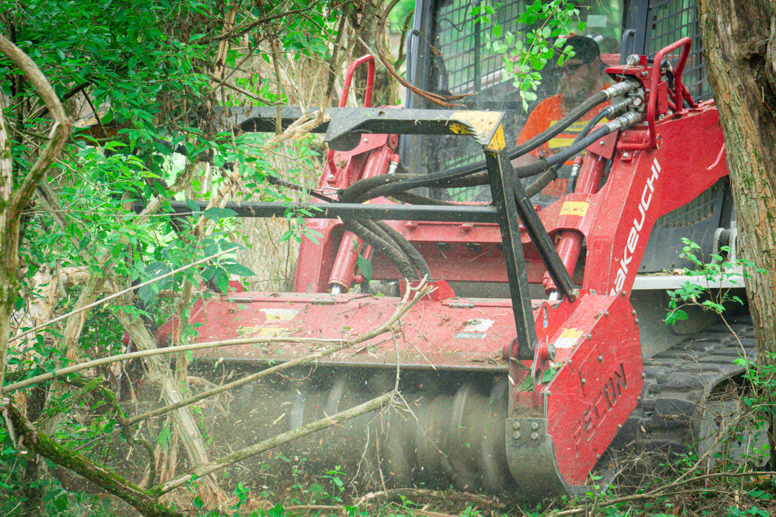 Close view of a Fecon mulching head on a Brushworks Takeuchi grinding a honeysuckle thicket