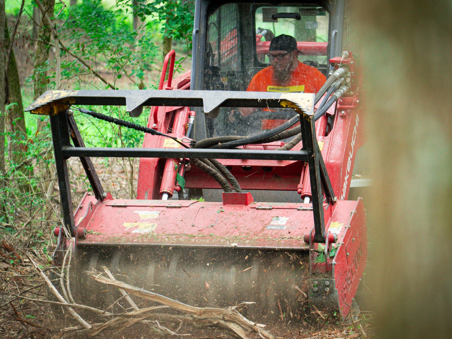 Brushworks operator inside the real Takeuchi TL12 while clearing wooded growth