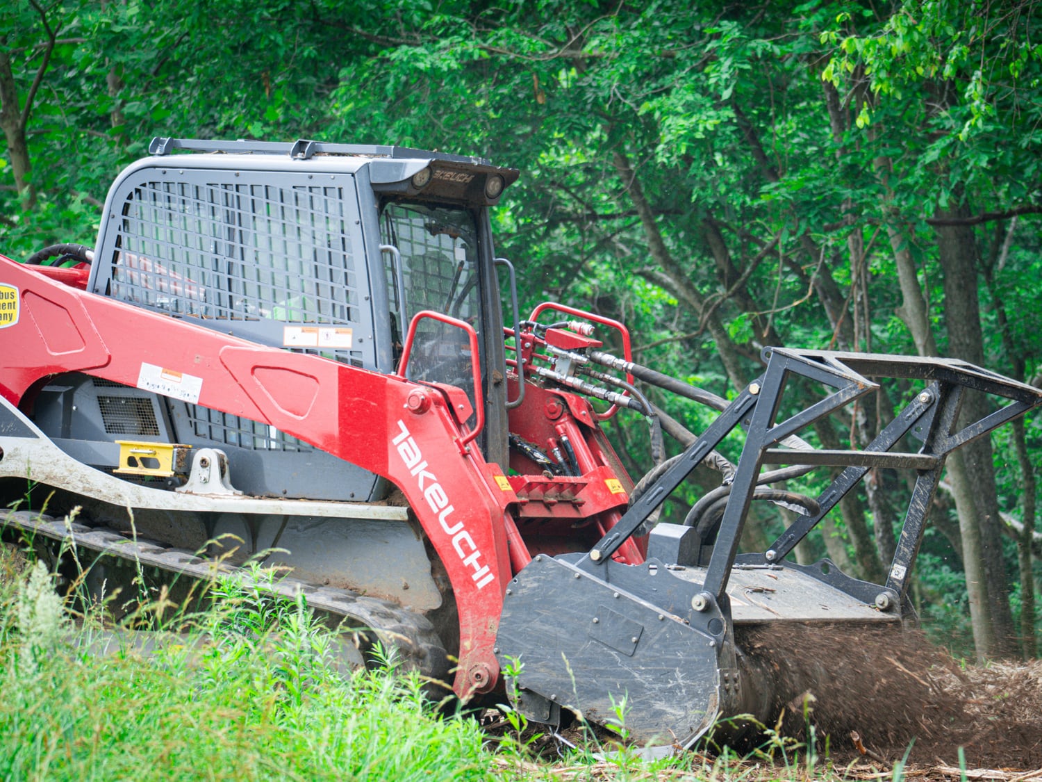 Real Takeuchi TL12 and Fecon mulching head clearing a wooded jobsite