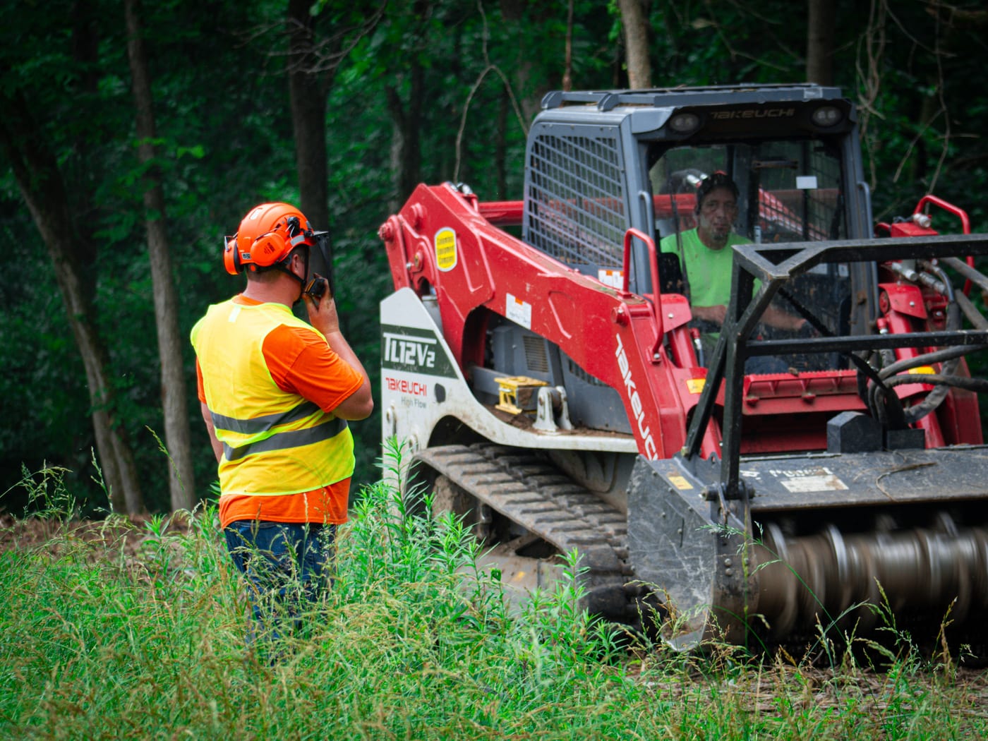 Brushworks team member working near the mulching head on a wooded jobsite