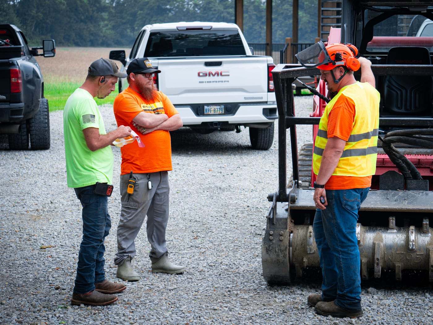 Brushworks crew discussing the work plan beside forestry mulching equipment